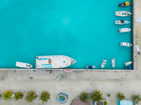 Aerial view of turquoise waters embrace boats docked at the pier contrasting against the sandy shore and tropical trees Vashafaru Island Maldives. Aerial view of turquoise waters embrace boats docked at the pier contrasting against the sandy shore and tropical trees Vashafaru Island Maldives.
