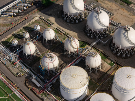 Aerial view of large white spherical and cylindrical industrial storage tanks and pipelines at an industrial facility in Bajos de Haina San Cristobal Province Dominican Republic.