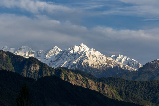 View of the snow capped peaks of the Hindu Kush mountains rising above the forested slopes of Kumrat Valley Khyber Pakhtunkhwa Pakistan. View of the snow capped peaks of the Hindu Kush mountains rising above the forested slopes of Kumrat Valley Khyber Pakhtunkhwa Pakistan.