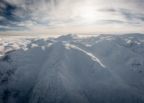 Aerial view of the snow covered peaks and rugged mountain landscape surrounding Gaustablikk Fjellresort under a bright winter sky in Rjukan Telemark Norway. Aerial view of the snow covered peaks and rugged mountain landscape surrounding Gaustablikk Fjellresort under a bright winter sky in Rjukan Telemark Norway.