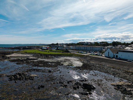 Aerial view of Donaghadee Harbour with its rocky shoreline coastal buildings and calm sea under a bright blue sky in Donaghadee Northern Ireland United Kingdom. Aerial view of Donaghadee Harbour with its rocky shoreline coastal buildings and calm sea under a bright blue sky in Donaghadee Northern Ireland United Kingdom.