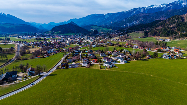 Aerial view of green meadows meet quaint houses nestled near the majestic snow dusted mountains in the Windischgarsten valley Windischgarsten Upper Austria Austria. Aerial view of green meadows meet quaint houses nestled near the majestic snow dusted mountains in the Windischgarsten valley Windischgarsten Upper Austria Austria.