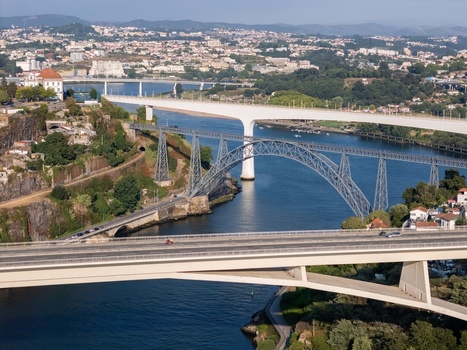 Aerial view of Ponte Infante Dom Henrique bridge spanning the Douro River with historic and modern structures green hills and urban development in Vila Nova de Gaia Porto Portugal.