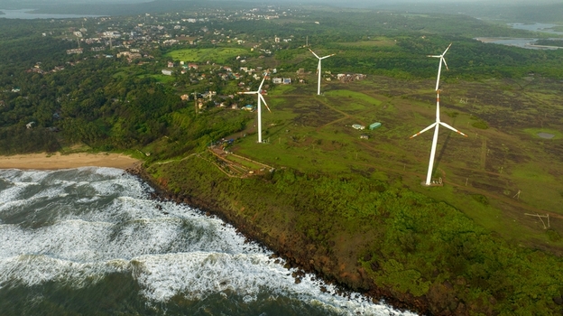 Aerial view of Devgad Windmills situated on a green coastal cliff overlooking the Arabian Sea with lush vegetation and nearby residential buildings in Devgad Maharashtra India. Aerial view of Devgad Windmills situated on a green coastal cliff overlooking the Arabian Sea with lush vegetation and nearby residential buildings in Devgad Maharashtra India.