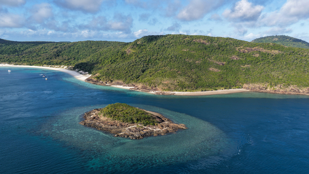 Aerial view of Haslewood Island featuring lush green vegetation rocky shores and vibrant turquoise coral reefs in the Whitsundays Queensland Australia. Aerial view of Haslewood Island featuring lush green vegetation rocky shores and vibrant turquoise coral reefs in the Whitsundays Queensland Australia.