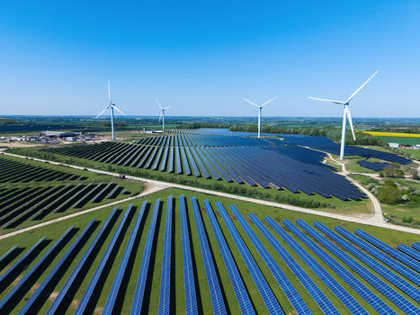 Aerial view of Chelveston Wind Farm featuring rows of solar panels and tall wind turbines under a clear blue sky in the rural landscape of Wellingborough England United Kingdom. Aerial view of Chelveston Wind Farm featuring rows of solar panels and tall wind turbines under a clear blue sky in the rural landscape of Wellingborough England United Kingdom.