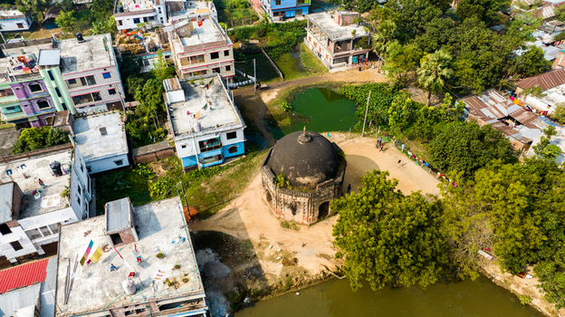 Aerial view of the historic Rohanpur Octagonal Tomb surrounded by residential buildings lush trees and a pond in Rohanpur Rajshahi Division Bangladesh.