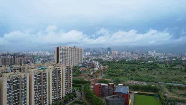 Aerial view of Gurugram skyscrapers and green fields India.