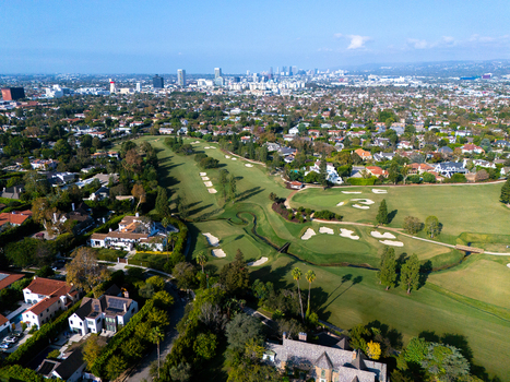 Aerial view of Wilshire Country Club with green fairways sand bunkers and surrounding residential neighborhoods under the Los Angeles skyline Los Angeles California United States. Aerial view of Wilshire Country Club with green fairways sand bunkers and surrounding residential neighborhoods under the Los Angeles skyline Los Angeles California United States.