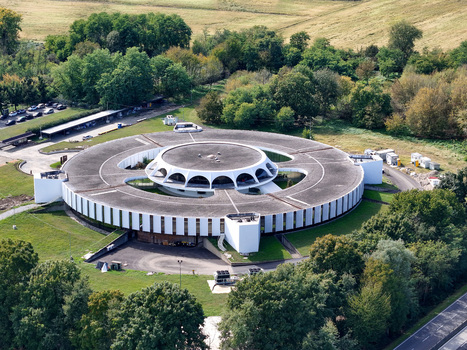 Aerial view of the Argotec SpacePark a modern circular building surrounded by lush green trees and rolling fields in San Mauro Torinese Piemonte Italy.