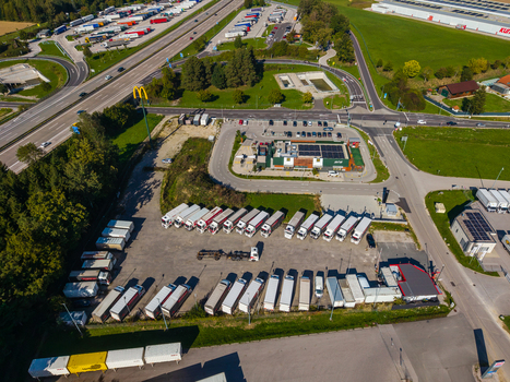 Aerial view of Logistikzentrum Allhaming with rows of parked semi trucks a nearby highway and surrounding green fields in Allhaming Oberosterreich Austria. Aerial view of Logistikzentrum Allhaming with rows of parked semi trucks a nearby highway and surrounding green fields in Allhaming Oberosterreich Austria.