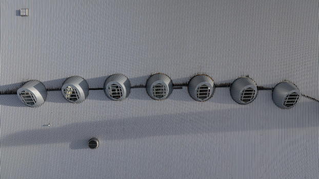 Aerial view of a corrugated metal shopping mall roof featuring a row of circular skylights in Iceland.