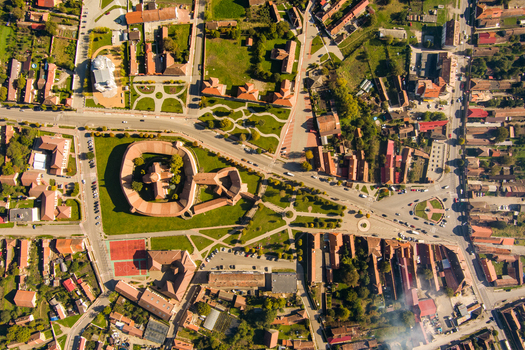 Aerial view of the historic Prejmer Fortified Church surrounded by green lawns residential rooftops and intersecting streets in Prejmer Brasov Romania. Aerial view of the historic Prejmer Fortified Church surrounded by green lawns residential rooftops and intersecting streets in Prejmer Brasov Romania.