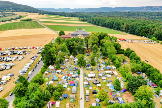 Aerial view of Schloss Jagersburg with a large campsite full of tents surrounded by lush trees and agricultural fields in Eggolsheim Bayern Germany. Aerial view of Schloss Jagersburg with a large campsite full of tents surrounded by lush trees and agricultural fields in Eggolsheim Bayern Germany.