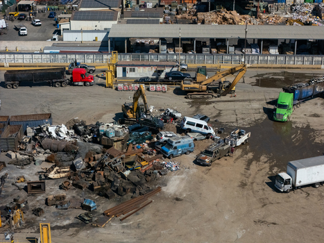 Aerial view of a scrap metal recycling facility with excavators piles of metal and trucks in an industrial yard in Carson California United States.