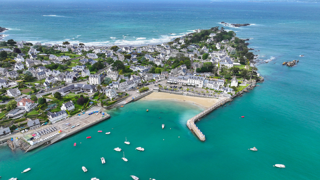 Aerial view of the Locquirec peninsula featuring the harbor sandy beach and traditional stone houses along the turquoise coastline in Locquirec Brittany France. Aerial view of the Locquirec peninsula featuring the harbor sandy beach and traditional stone houses along the turquoise coastline in Locquirec Brittany France.
