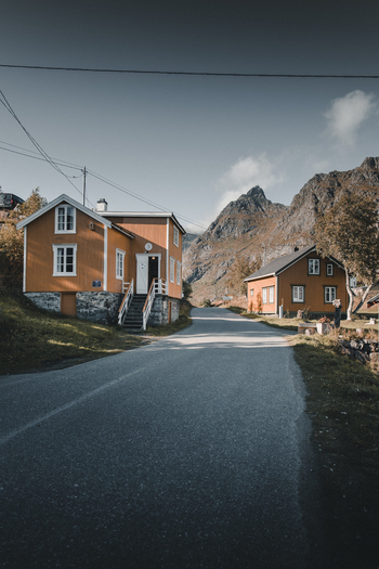 A Nordland Norway 08 September 2022 View of traditional orange wooden houses along a quiet road with dramatic mountains in the background.