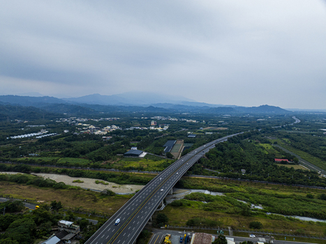 Aerial view of a highway bridge spanning a river surrounded by lush green landscape and distant mountains in Jiuru Township Pingtung County Taiwan. Aerial view of a highway bridge spanning a river surrounded by lush green landscape and distant mountains in Jiuru Township Pingtung County Taiwan.