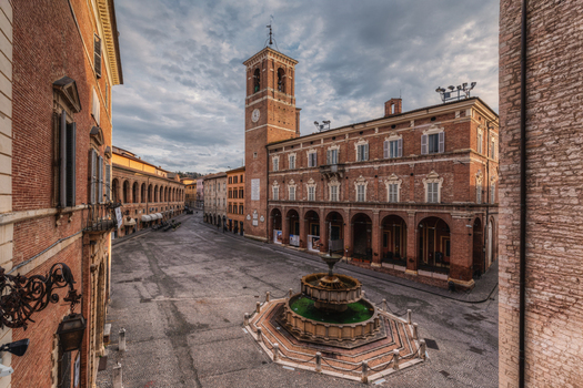 View of the historic Piazza del Comune with its central fountain clock tower and surrounding brick architecture in Fabriano Marche Italy. View of the historic Piazza del Comune with its central fountain clock tower and surrounding brick architecture in Fabriano Marche Italy.