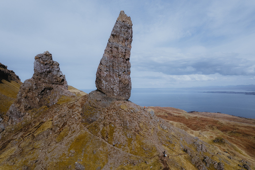 Aerial view of The Storr a dramatic basalt rock formation on the Isle of Skye featuring rugged terrain grassy slopes and the sea in the background Portree Scotland United Kingdom. Aerial view of The Storr a dramatic basalt rock formation on the Isle of Skye featuring rugged terrain grassy slopes and the sea in the background Portree Scotland United Kingdom.