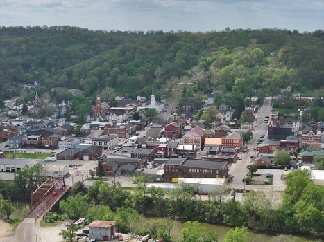Aerial view of historic brick buildings church steeples and a bridge over a river nestled against lush green hills in Aurora Indiana United States. Aerial view of historic brick buildings church steeples and a bridge over a river nestled against lush green hills in Aurora Indiana United States.