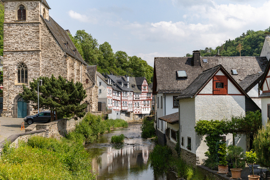 View of historic half timbered houses and the stone Trinity Church along the Elzbach river under a bright sky Monreal Rhineland Palatinate Germany. View of historic half timbered houses and the stone Trinity Church along the Elzbach river under a bright sky Monreal Rhineland Palatinate Germany.