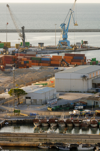Aerial view of Ancona Port featuring colorful shipping containers industrial cranes and a fleet of fishing boats docked in the harbor in Ancona Marche Italy. Aerial view of Ancona Port featuring colorful shipping containers industrial cranes and a fleet of fishing boats docked in the harbor in Ancona Marche Italy.