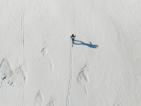 Aerial view of a person skiing across a vast snow covered landscape on the south slope of Mount Etna in Nicolosi Sicilia Italy. Aerial view of a person skiing across a vast snow covered landscape on the south slope of Mount Etna in Nicolosi Sicilia Italy.