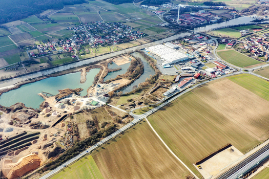 Aerial view of the town of Buttenheim featuring industrial buildings a quarry and agricultural fields along a river in Buttenheim Bavaria Germany. Aerial view of the town of Buttenheim featuring industrial buildings a quarry and agricultural fields along a river in Buttenheim Bavaria Germany.