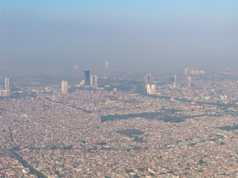Aerial view of the sprawling cityscape with dense urban development high rise buildings and hazy atmosphere in Surabaya East Java Indonesia. Aerial view of the sprawling cityscape with dense urban development high rise buildings and hazy atmosphere in Surabaya East Java Indonesia.