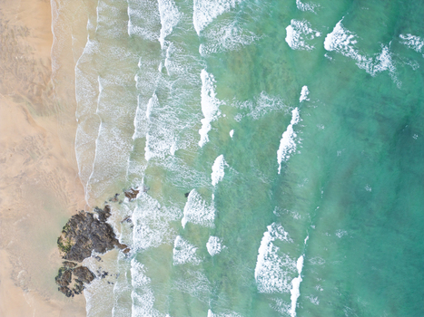 Aerial view of Godrevy Beach with turquoise ocean waves crashing on the sandy shore and dark rocks in Gwithian England United Kingdom. Aerial view of Godrevy Beach with turquoise ocean waves crashing on the sandy shore and dark rocks in Gwithian England United Kingdom.