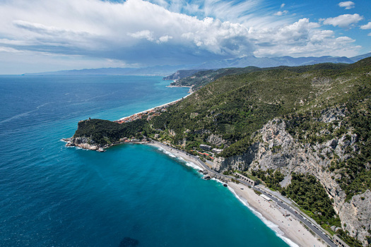 Aerial view of Promontorio di Varigotti with turquoise sea steep green cliffs and sandy beaches in Varigotti Liguria Italy. Aerial view of Promontorio di Varigotti with turquoise sea steep green cliffs and sandy beaches in Varigotti Liguria Italy.