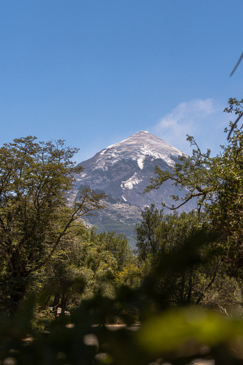 View of Lanin volcano with its snow capped peak rising above the lush green forest under a clear blue sky in Huiliches Department Neuquen Province Argentina. View of Lanin volcano with its snow capped peak rising above the lush green forest under a clear blue sky in Huiliches Department Neuquen Province Argentina.