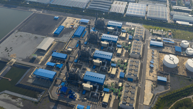 Aerial view of the Gulf Pluak Daeng Power Plant GPD featuring blue industrial buildings tall smokestacks and circular storage tanks in Map Yang Phon Rayong Thailand. Aerial view of the Gulf Pluak Daeng Power Plant GPD featuring blue industrial buildings tall smokestacks and circular storage tanks in Map Yang Phon Rayong Thailand.