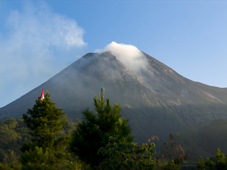 Aerial view of Bunker Kaliadem Merapi and the smoking peak of Mount Merapi volcano surrounded by lush pine trees in Kecamatan Pakem Daerah Istimewa Yogya Indonesia. Aerial view of Bunker Kaliadem Merapi and the smoking peak of Mount Merapi volcano surrounded by lush pine trees in Kecamatan Pakem Daerah Istimewa Yogya Indonesia.