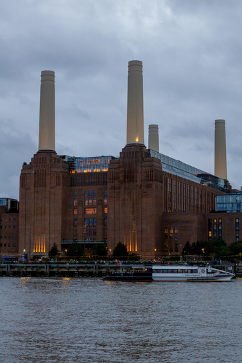 View of the iconic Battersea Power Station with its four chimneys and brick facade illuminated at dusk situated along the river Thames in London England United Kingdom. View of the iconic Battersea Power Station with its four chimneys and brick facade illuminated at dusk situated along the river Thames in London England United Kingdom.