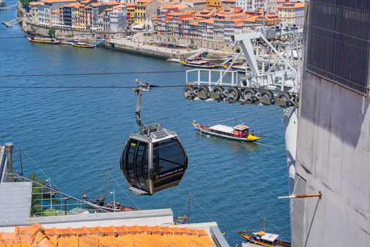 Aerial view of the cable car gliding over the Douro River with colorful buildings lining the riverbank Porto Porto District Portugal. Aerial view of the cable car gliding over the Douro River with colorful buildings lining the riverbank Porto Porto District Portugal.