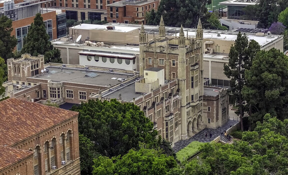 Aerial view of Royce Hall at the UCLA Campus featuring its iconic Romanesque Revival architecture red brick facade and twin towers surrounded by trees in Westwood California United States.