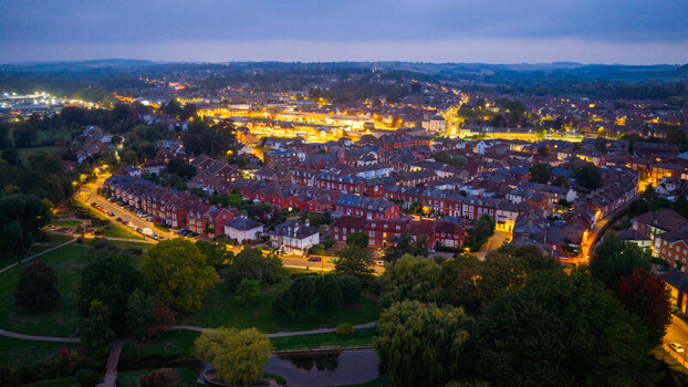 Aerial view of the historic city of Salisbury at dusk featuring illuminated residential streets dense housing and surrounding parkland in Salisbury England United Kingdom. Aerial view of the historic city of Salisbury at dusk featuring illuminated residential streets dense housing and surrounding parkland in Salisbury England United Kingdom.