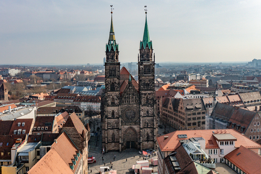 Aerial view of the historic St. Lorenz Church with its twin Gothic spires rising above the red tiled rooftops of the old town under a clear sky in Nurnberg Bayern Germany.