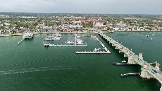 Aerial view of the Bridge of Lions spanning the Matanzas River a marina with docked boats and the historic city skyline under an overcast sky in St. Augustine Florida United States.