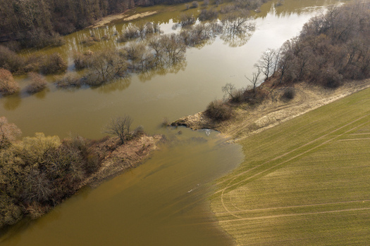 Aerial view of a flooded river overflowing into green agricultural fields with bare trees standing in murky water Kaniukai Kaunas County Lithuania. Aerial view of a flooded river overflowing into green agricultural fields with bare trees standing in murky water Kaniukai Kaunas County Lithuania.