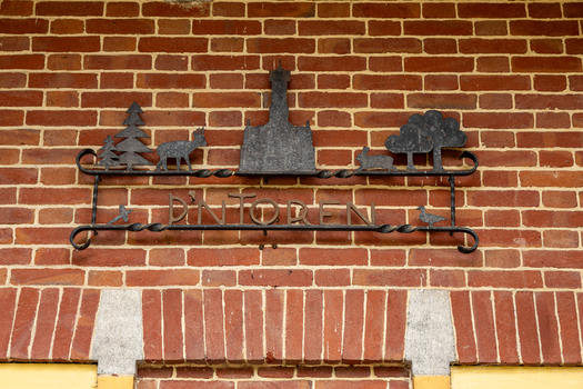 View of the metal sign for De Brandtoren featuring silhouettes of a tower a deer and a rabbit mounted on a red brick wall in Esbeek Noord Brabant Netherlands.
