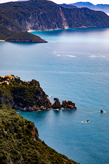 Aerial view of the rugged coastline with turquoise waters rocky cliffs and lush Mediterranean vegetation in Corfu Ionian Islands Greece. Aerial view of the rugged coastline with turquoise waters rocky cliffs and lush Mediterranean vegetation in Corfu Ionian Islands Greece.