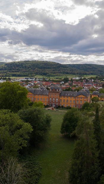 Aerial view of Schloss Lowenstein surrounded by lush green parkland and the town of Kleinheubach under a cloudy sky in Kleinheubach Bayern Germany. Aerial view of Schloss Lowenstein surrounded by lush green parkland and the town of Kleinheubach under a cloudy sky in Kleinheubach Bayern Germany.