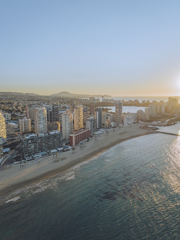 Aerial view of the coastal city with high rise buildings along the sandy beach calm sea waters and golden sunlight at sunset in Calp Valencian Community Spain. Aerial view of the coastal city with high rise buildings along the sandy beach calm sea waters and golden sunlight at sunset in Calp Valencian Community Spain.