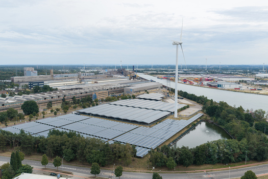 Aerial view of the Haven Genk solar power plant featuring extensive photovoltaic panels a wind turbine and industrial infrastructure in Genk Vlaanderen Belgium.
