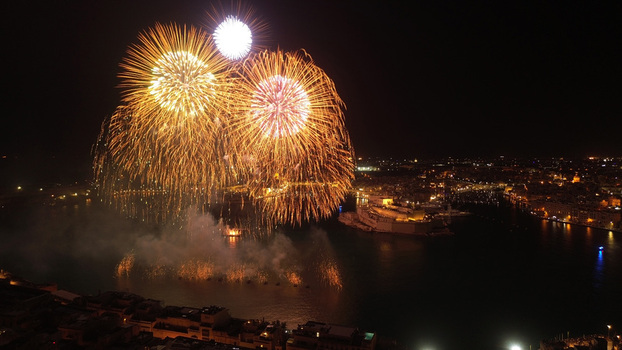 Aerial view of vibrant fireworks illuminating the night sky over the harbor and historic city lights in Valletta Port Region Malta. Aerial view of vibrant fireworks illuminating the night sky over the harbor and historic city lights in Valletta Port Region Malta.