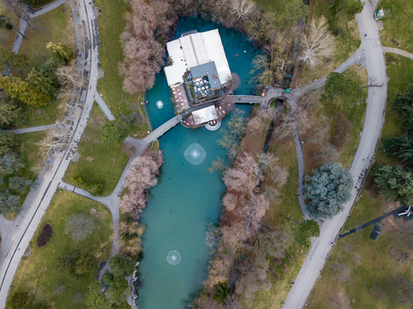 Aerial view of a public park featuring a turquoise pond with a central pavilion building and walking paths in Bologna Emilia Romagna Italy. Aerial view of a public park featuring a turquoise pond with a central pavilion building and walking paths in Bologna Emilia Romagna Italy.