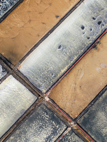 Aerial view of salt pans showcasing geometric patterns and textured surfaces of evaporation ponds in Vietnam. Aerial view of salt pans showcasing geometric patterns and textured surfaces of evaporation ponds in Vietnam.